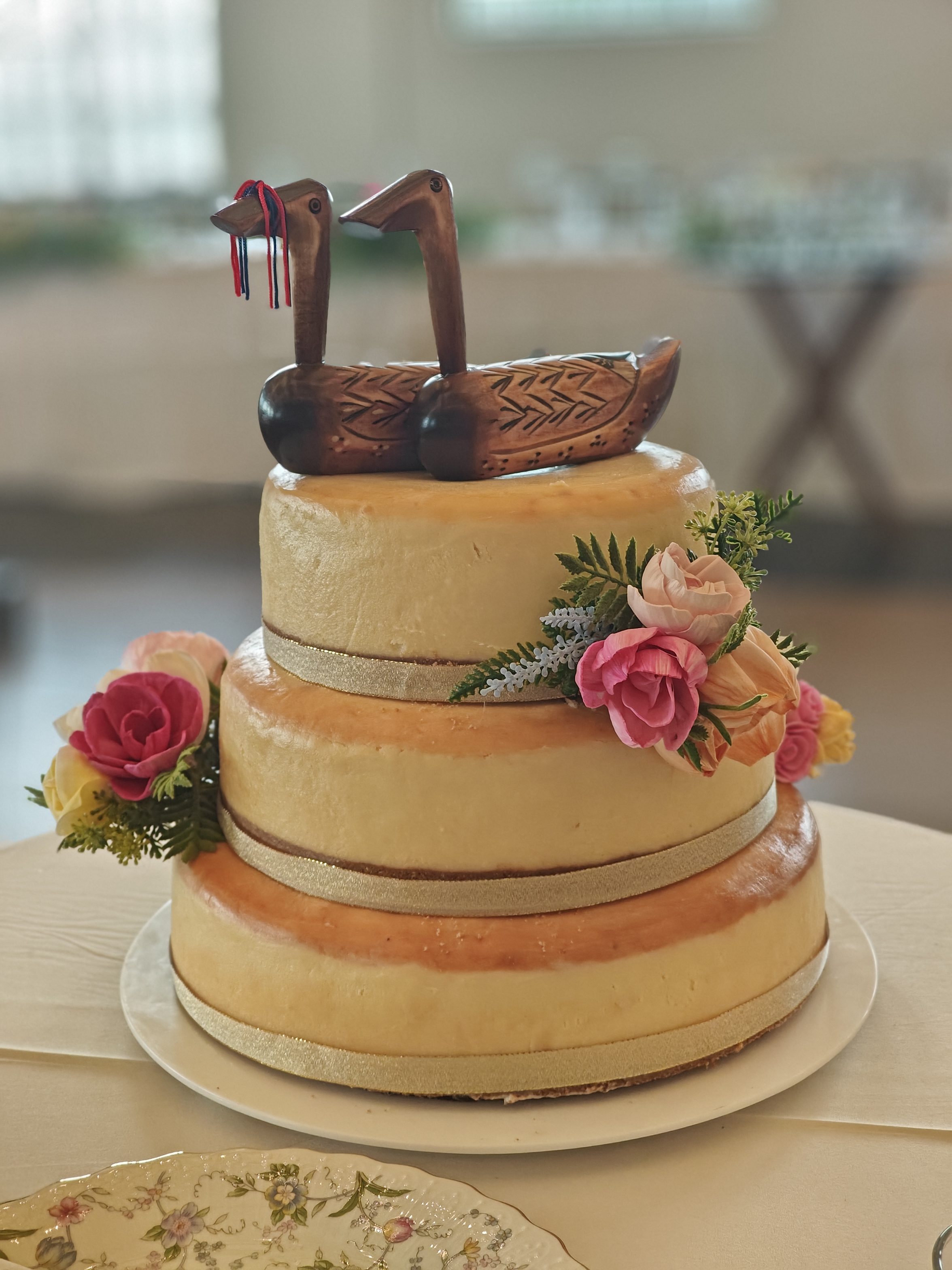Three-tier naked cheesecake wedding cake topped with wooden ducks