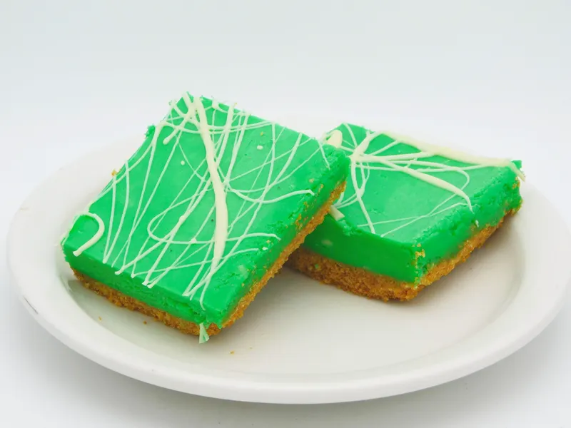 White chocolate raspberry sheet cheesecake pre-sliced on a tray