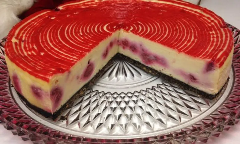 Red-swirled Hank's cheesecake on a glass cake stand