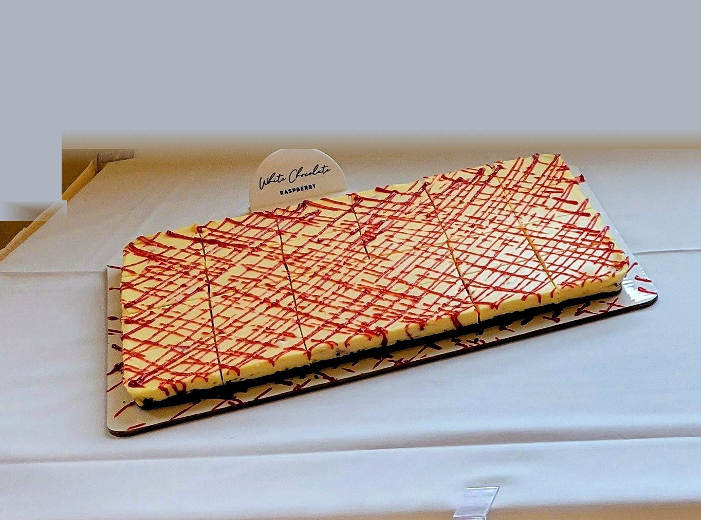 White chocolate raspberry sheet cheesecake pre-sliced on a tray