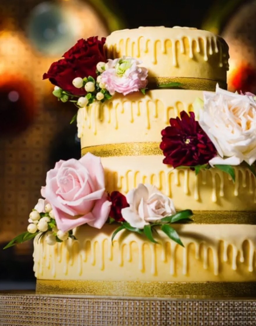 Four-tier white chocolate drip cheesecake with red and pink florals
